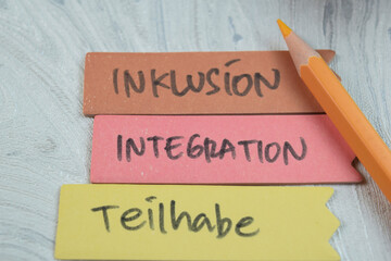 Concept of Inklusion, Integration, Teilhabe write on sticky notes isolated on Wooden Table.