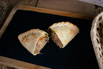Argentinian chaparrita empanada, cut on a slate and wooden plate, stuffed empanada, vertical flat