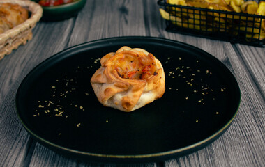 Argentinian delicacy, baked basket on black plate with potatoes on wooden table