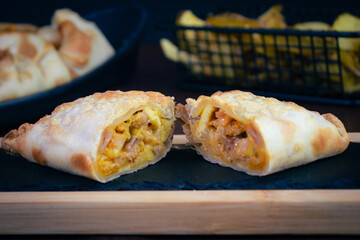 Argentinian chicken empanada, visible filling, potato wedges and premium cutlery