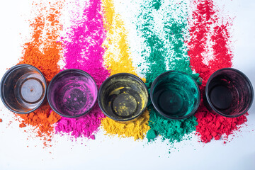 Colorful holi powder on white background and empty black small boxes on top of it. Top view