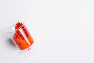 Red holi powder in glass cup on white background with copy space.