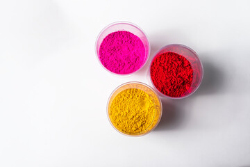 Colorful holi powder in plastic containers isolated on white background.