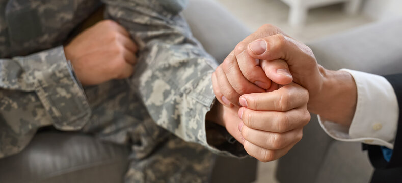 Mature psychologist working with soldier in office, closeup