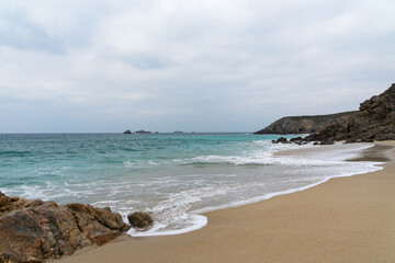 Le littoral breton, entre falaises et plages, dévoile un spectacle saisissant : sable, rochers et eaux turquoises sous un ciel couvert.