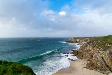 Fototapeta premium Des falaises majestueuses offrent une vue panoramique sur la mer d'Iroise, où les eaux turquoises caressent la plage de sable blanc, un spectacle saisissant.