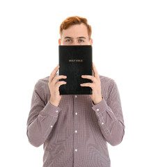 Young redhead man with Bible isolated on white background
