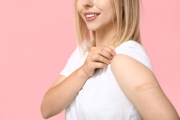Young woman with medical patch on arm against pink background. Vaccination concept