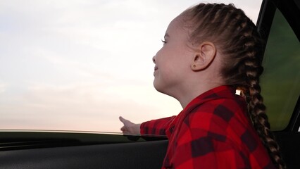 little happy girl child kid looking sunset from car window, happy family, evening road trip, day's...