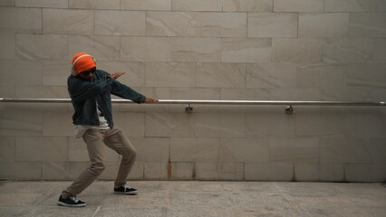 Asian smart hipster show energetic break dance with gray background at building while wearing...