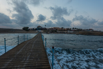 long jetty to the resort in egypt with strong waves and clouds