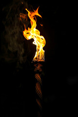 Lit matchstick with fire and smoke coming out of it on black background.