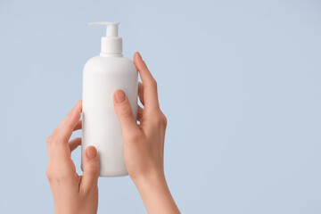 Female hands with bottle of natural cream on color background, closeup