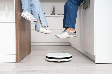 Family with robot vacuum cleaner in kitchen