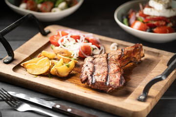 Barbecue grilled lamb chops on wooden desk with potatoes and tomatoes serving in restaurant