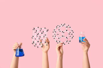 Female hands holding molecular models with filled flask and bottle on pink background. Chemistry...