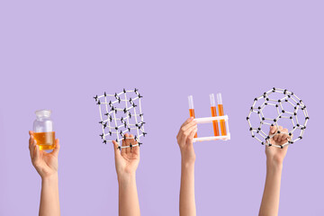 Female hands holding filled test tubes with bottle and molecular models on lilac background....