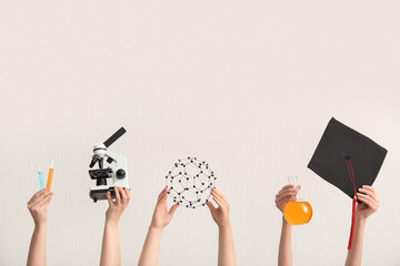 Female hands holding graduation hat with filled flask, microscope and molecular model on white...
