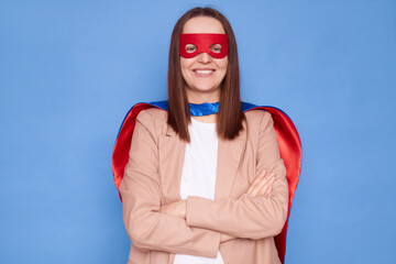 Super hero Caucasian woman wearing mask posing with crossed arms isolated over blue background...