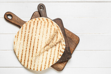 Fresh lavash, wooden board and ears of wheat on white wooden background
