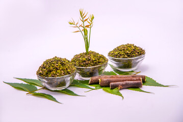 Close up top view of Indian ayurvedic herb Neem /Azadirachta Indica green leaves on white background with dry powder in glass dish with selective focus.Medicinal Neem leaves with neem paste in spoon 