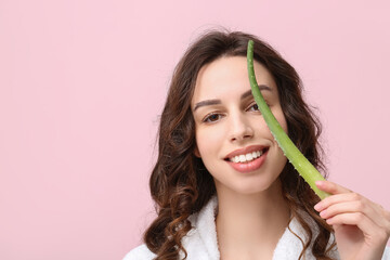 Beautiful young woman with aloe vera on pink background