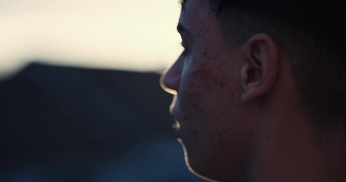 A young man with acne and a few blemishes on his face. He is looking at the camera