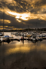 Pwllheli marina, with boats and yachts moored, in late evening sunlight. Pwllheli is a coastal...