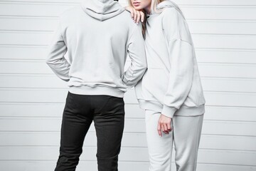 The couple wears blank streetwear hoodies. Man and woman sweatshirt design logo mock-up.