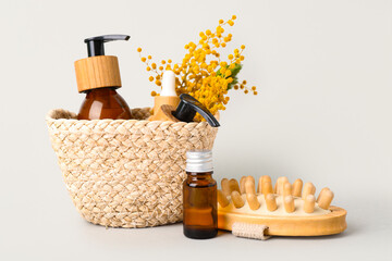 Composition with natural cosmetic products and mimosa flowers in wicker basket on white background