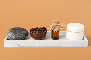 Tray with spa stone, bowl of coffee beans, serum bottle and jar of face cream on brown background, closeup