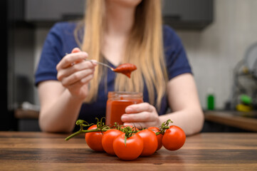 Obraz na płótnie Canvas Kobieta je domowy przecier, koncentrat pomidorowy ze słoika