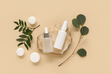 Composition with stone, twigs, jars and bottles of cosmetic products on beige background