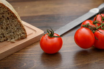 Dojrzałe czerwone pomidory malinowe obok chleba na kanapki, jedzenie na surowo  - obrazy, fototapety, plakaty