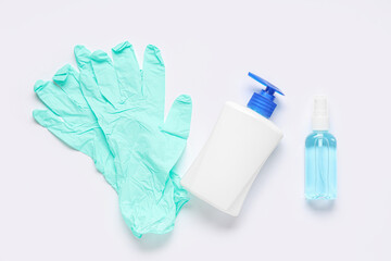 Rubber gloves with bottles of sanitizer on white background