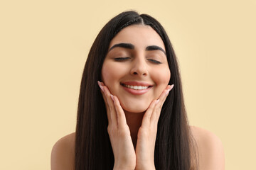 Beautiful young happy woman with healthy long hair on beige background