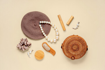 Cap, pearl necklace and wicker bag on beige background