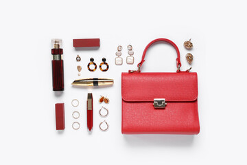 Red leather bag, bottle of perfume and beautiful jewellery on white background
