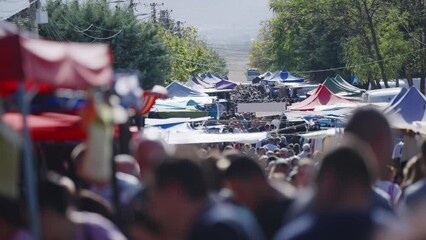 A busy outdoor market with many people and tents. Scene is lively and bustling