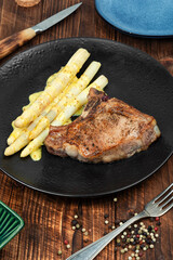 Barbecue steak with asparagus on a wooden table.