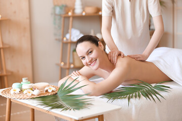 Obraz na płótnie Canvas Happy young woman getting back massage in spa salon