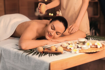 Obraz na płótnie Canvas Beautiful young woman getting back scrub massage in spa salon