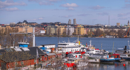 Wharf with fishing, tug and commuting boats, the district Kungsholmen in background, a sunny spring...