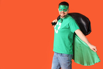 Young man dressed as eco superhero with garbage bag on orange background. Ecology concept