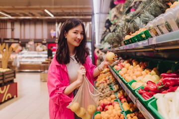 Young Korean woman shopping without plastic bags in grocery store. Vegan zero waste girl choosing...