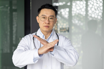 Asian mature doctor gesturing no with serious expression