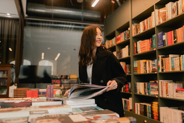 Pretty teen gen Z Korean student girl chooses book in a bookstore. Education training concept. Part...
