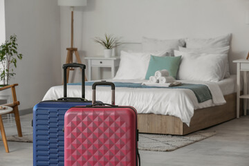 Interior of light hotel room with suitcases near bed, closeup