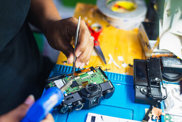 A skilled technician meticulously repairs the internal components of a digital camera on a...