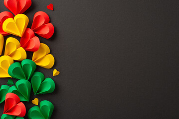 Bright paper hearts in red, yellow, and green colors arranged on a dark background represent joy...